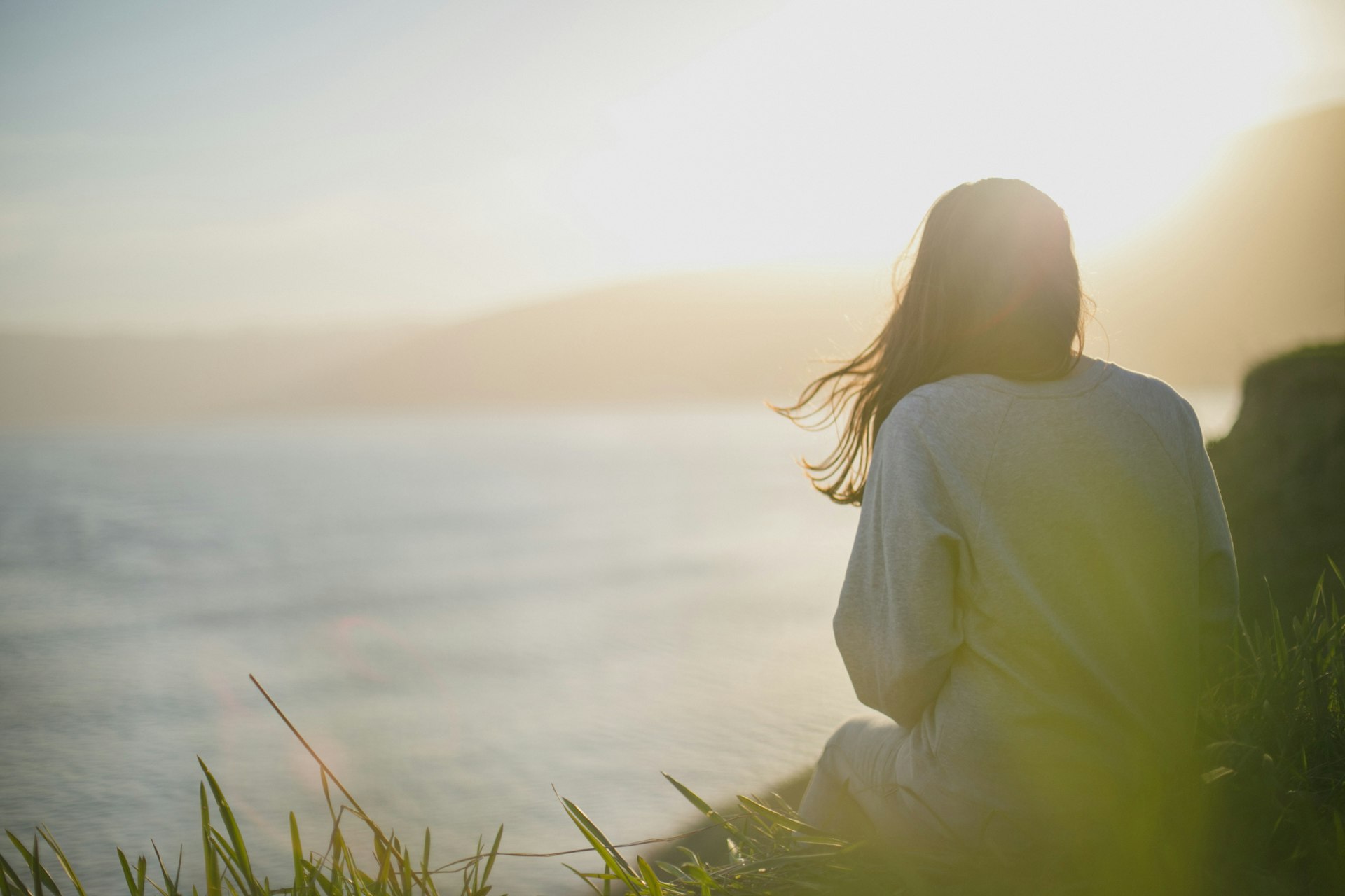 woman wearing gray long-sleeved shirt facing the sea woman wearing gray long-sleeved shirt facing the sea